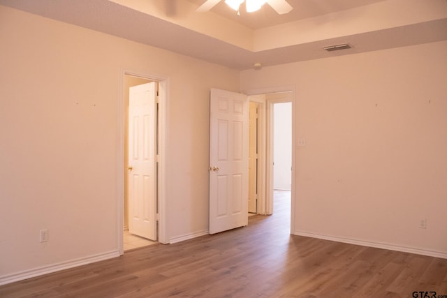 unfurnished room with hardwood / wood-style floors, ceiling fan, and a tray ceiling