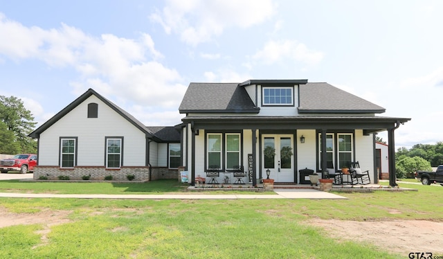 view of front facade with covered porch, french doors, a shingled roof, and a front lawn