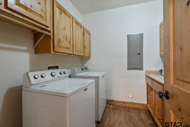 clothes washing area with electric panel, washing machine and dryer, wood-type flooring, and cabinets