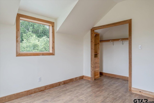 unfurnished bedroom with hardwood / wood-style floors, a closet, and vaulted ceiling