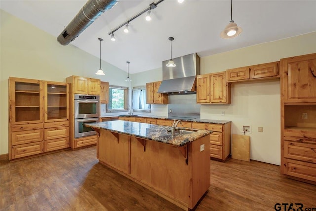 kitchen featuring extractor fan, dark stone counters, stainless steel double oven, a kitchen island, and dark wood-type flooring