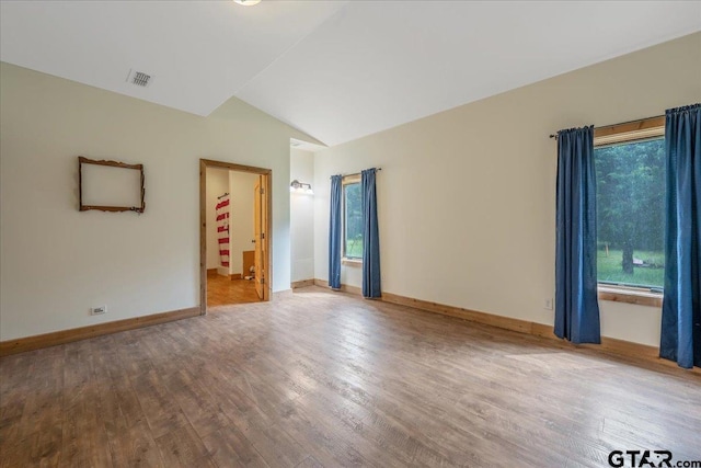 unfurnished room featuring hardwood / wood-style flooring and lofted ceiling