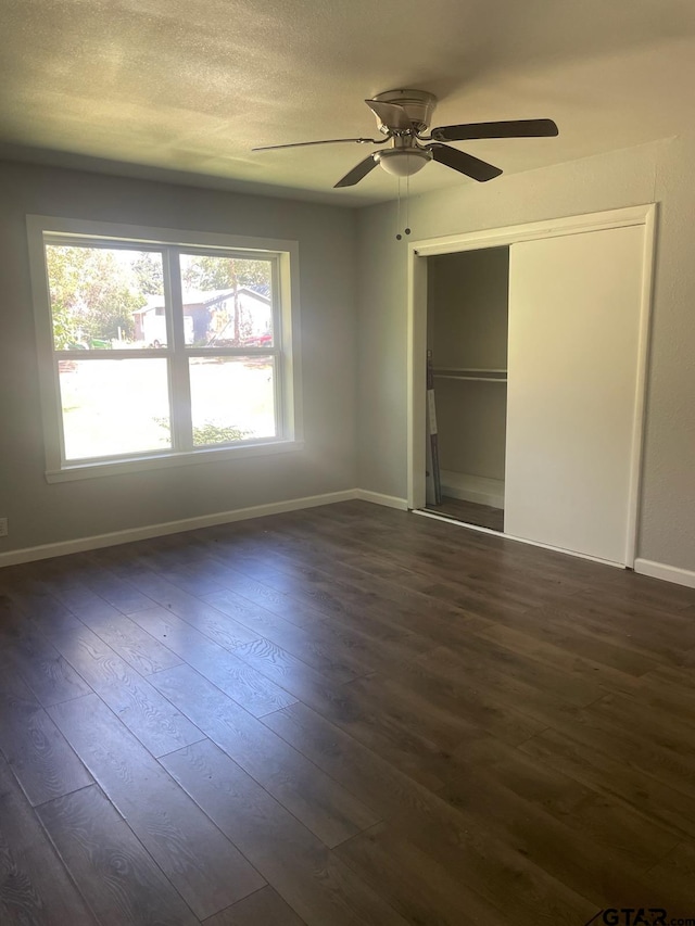 unfurnished bedroom with a textured ceiling, dark wood-type flooring, ceiling fan, and a closet