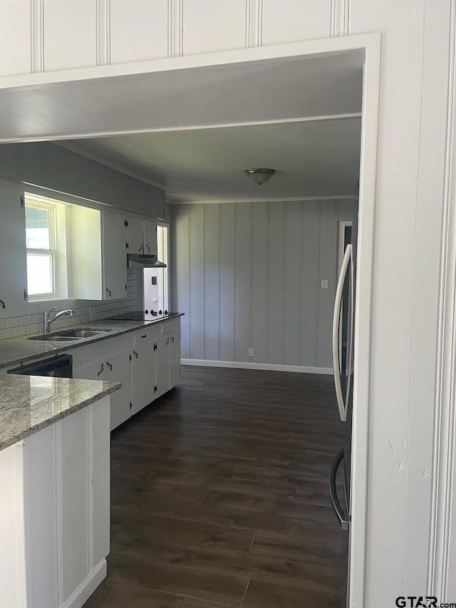 kitchen with dark wood-type flooring, light stone counters, white cabinets, decorative backsplash, and sink