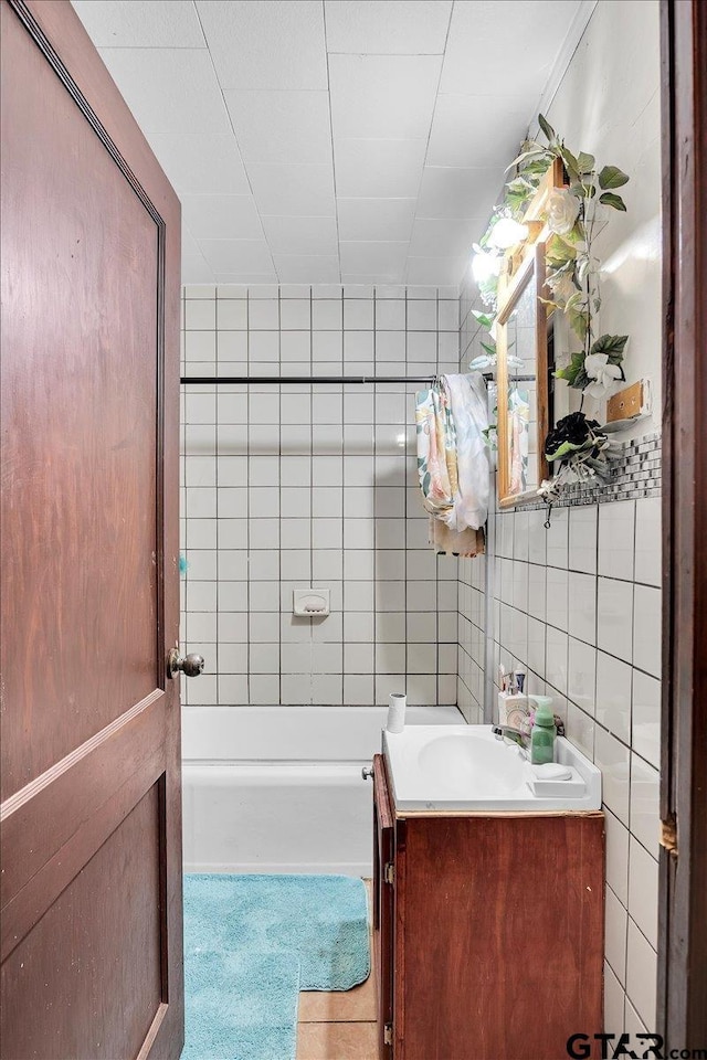 full bath featuring tile patterned flooring, tasteful backsplash, tile walls, and vanity