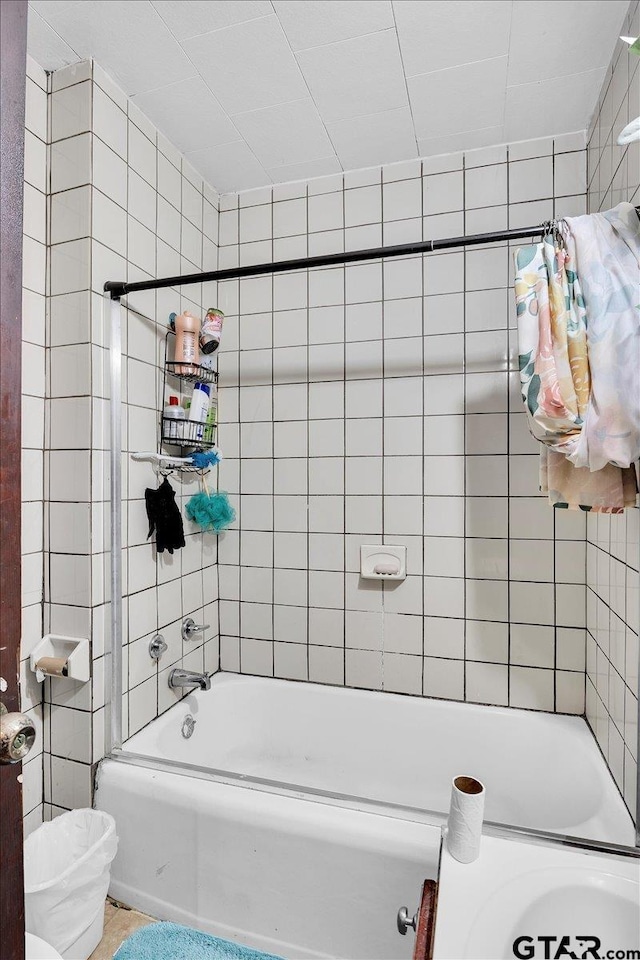 full bath featuring toilet, tile walls, and shower / tub combination