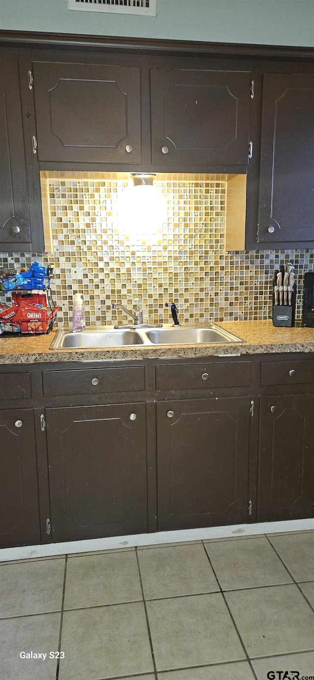 kitchen with tile patterned flooring, dark brown cabinets, and backsplash