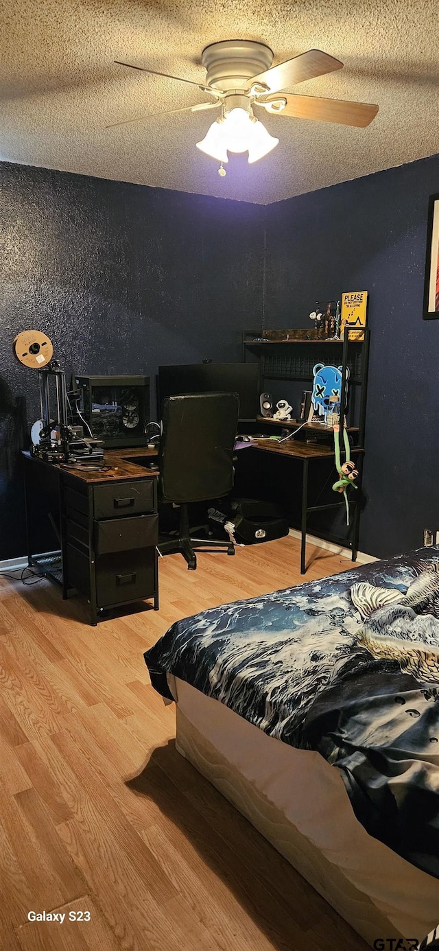 bedroom with hardwood / wood-style floors, a textured ceiling, and ceiling fan