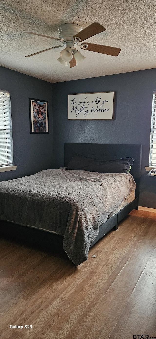 bedroom featuring ceiling fan, wood-type flooring, and a textured ceiling