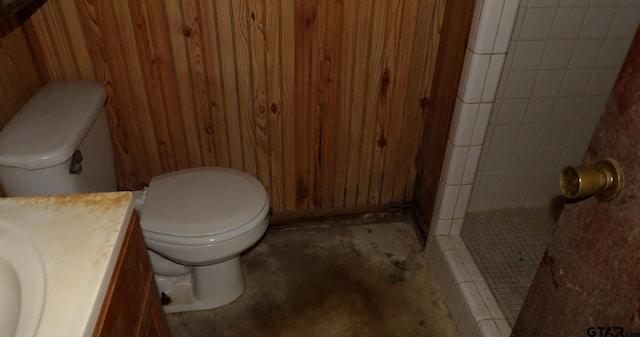915 John St, Jacksonville, TX 75766 - full bathroom with toilet, concrete flooring, vanity, a tile shower, and wood walls