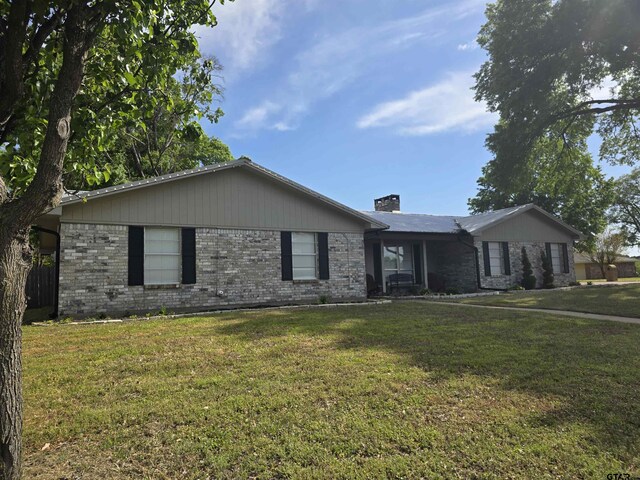single story home with a chimney, a front lawn, and brick siding