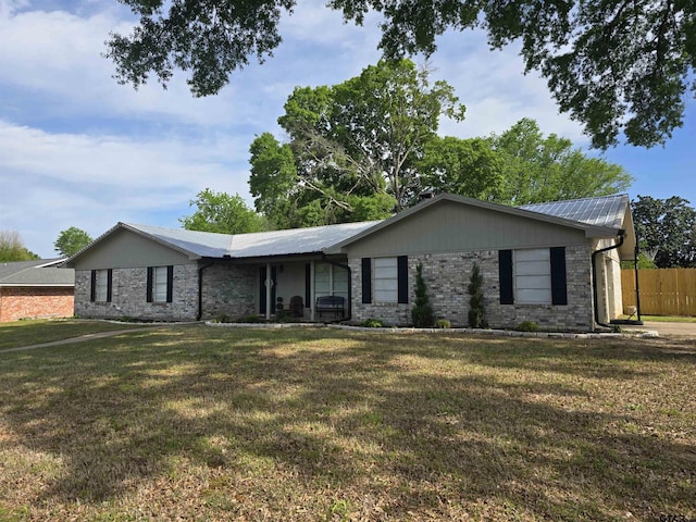 ranch-style house featuring a front yard, fence, and metal roof