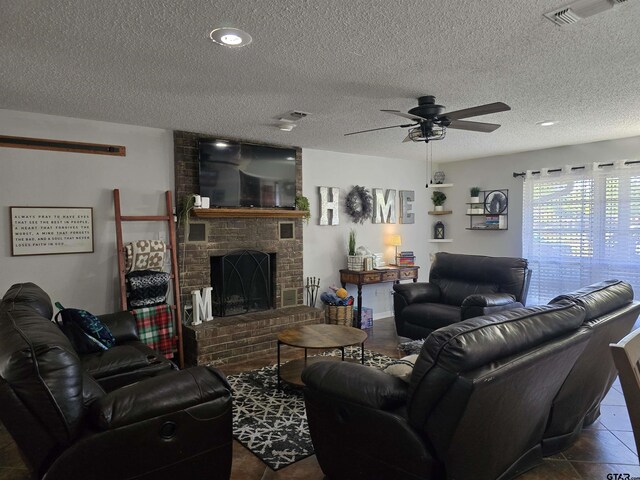 living room with a textured ceiling, a brick fireplace, a ceiling fan, and visible vents