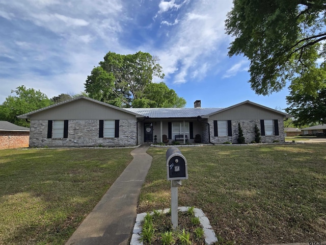 view of front of home featuring a chimney, a front yard, and brick siding