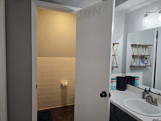 bathroom featuring tile walls, vanity, and a textured wall