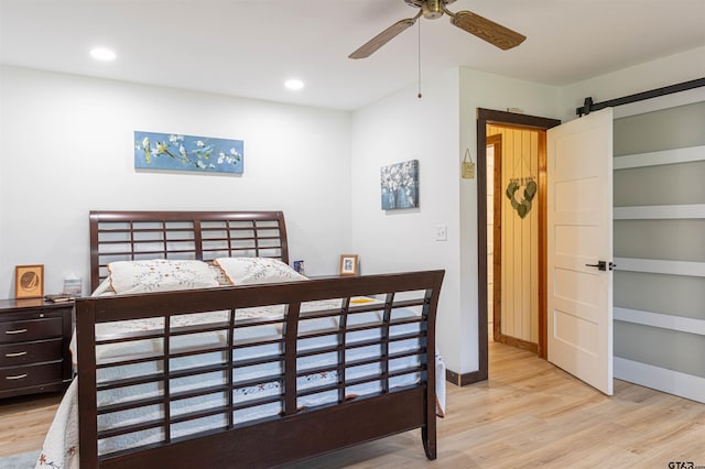 bedroom featuring a barn door, baseboards, light wood-style floors, and recessed lighting