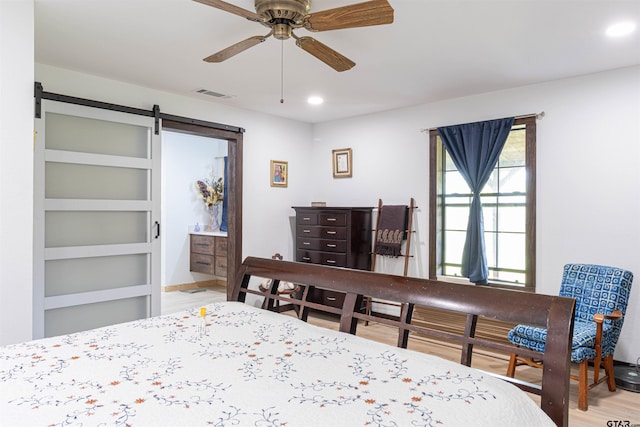 bedroom featuring recessed lighting, a barn door, ceiling fan, visible vents, and wood finished floors