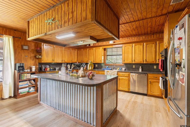 kitchen with dark countertops, stainless steel appliances, tasteful backsplash, and light wood-style flooring