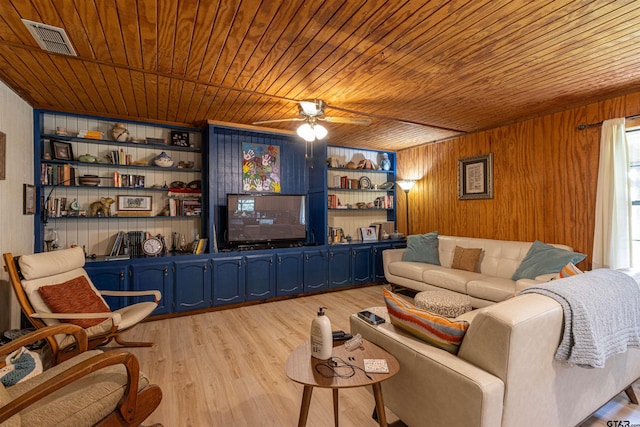 living area featuring wood ceiling, wooden walls, light wood finished floors, ceiling fan, and visible vents