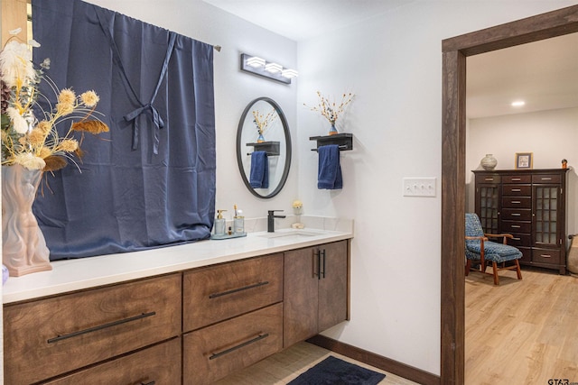 full bathroom with baseboards, wood finished floors, and vanity