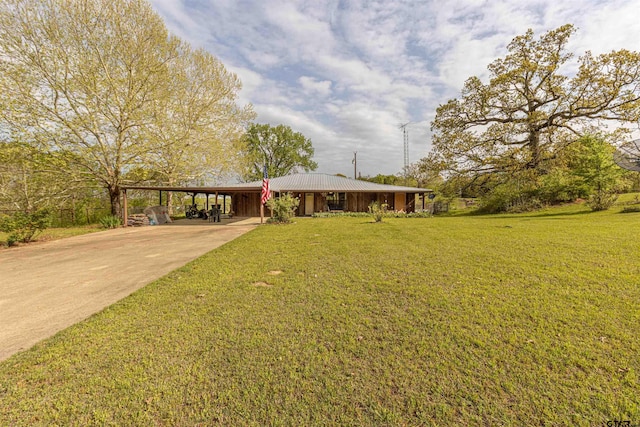 view of front facade with metal roof, concrete driveway, a front yard, and a carport