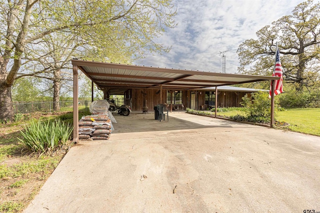 view of vehicle parking with a carport, fence, and concrete driveway