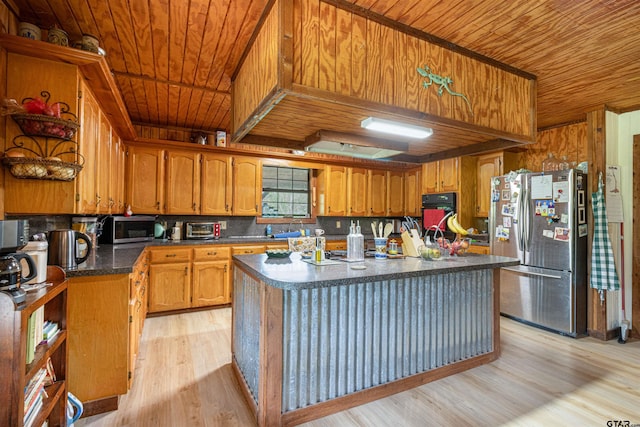 kitchen featuring light wood-style flooring, dark countertops, appliances with stainless steel finishes, brown cabinetry, and wood ceiling