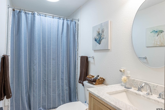 bathroom with toilet, vanity, a textured wall, and a shower with shower curtain