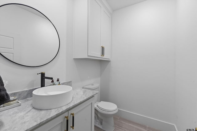 bathroom with toilet, vanity, and hardwood / wood-style flooring