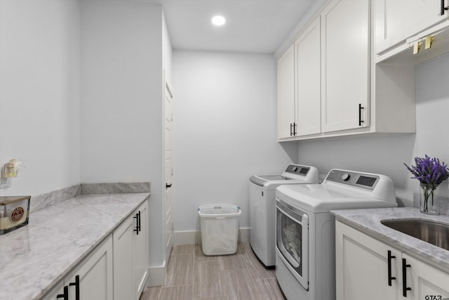 clothes washing area featuring washing machine and dryer and cabinets