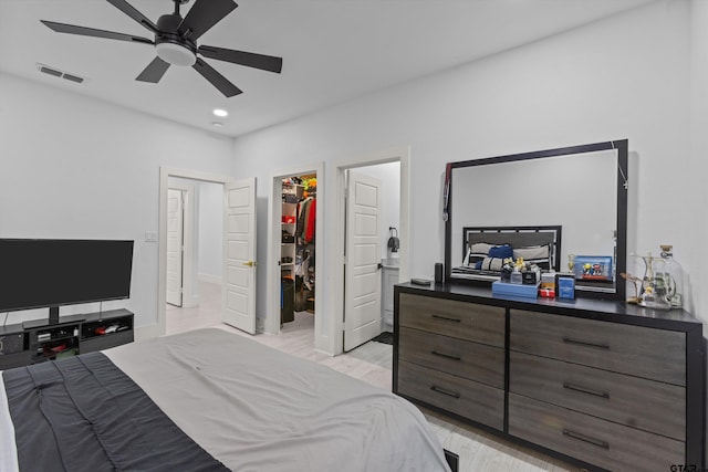 bedroom with ceiling fan, a closet, light hardwood / wood-style flooring, and a spacious closet