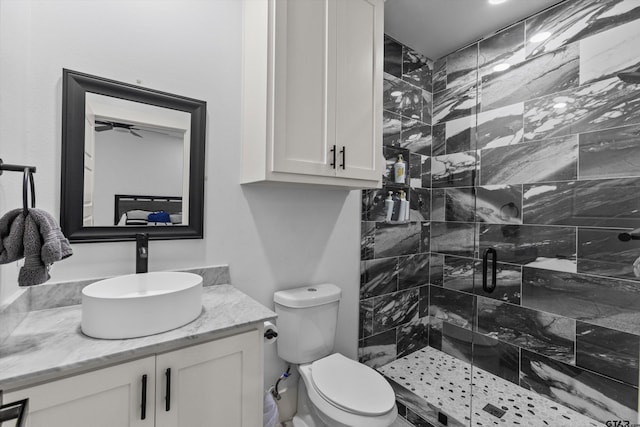 bathroom featuring toilet, vanity, ceiling fan, and a shower with shower door