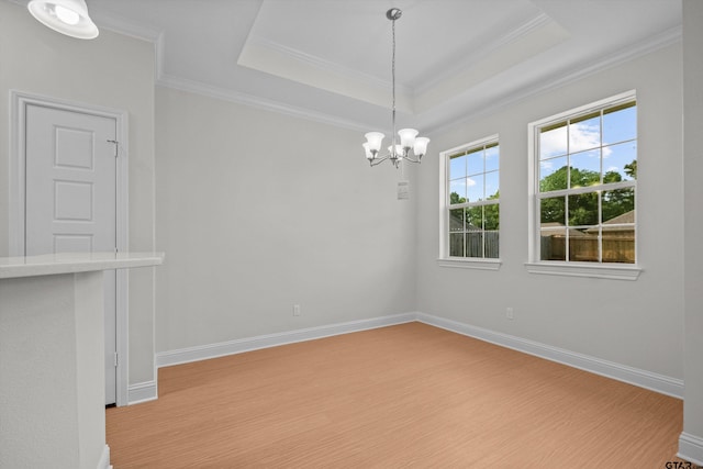 unfurnished room with light hardwood / wood-style floors, a notable chandelier, a tray ceiling, and ornamental molding