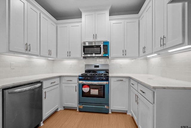 kitchen featuring white cabinets, stainless steel appliances, and backsplash