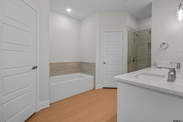 bathroom featuring plus walk in shower, vanity, and hardwood / wood-style floors