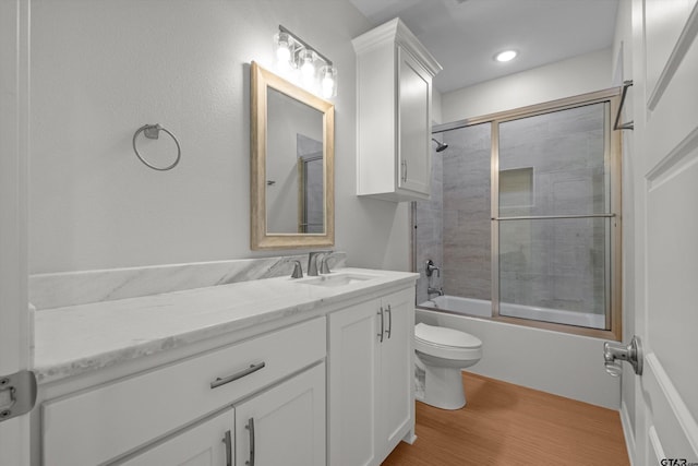 full bathroom featuring shower / bath combination with glass door, hardwood / wood-style flooring, toilet, and vanity