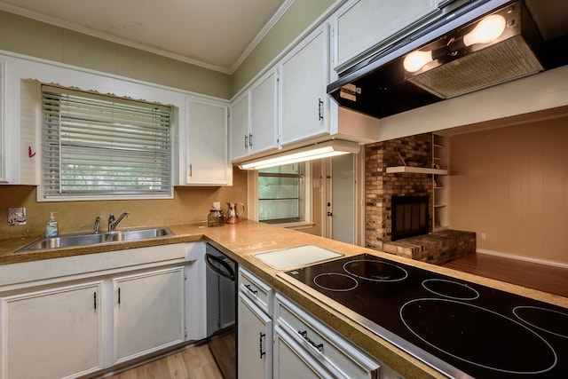 kitchen featuring crown molding, stovetop, a fireplace, white cabinetry, and sink