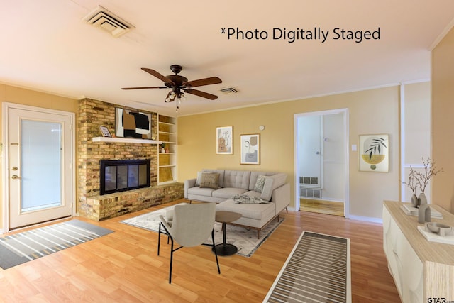 living room with wood-type flooring, a fireplace, ceiling fan, and ornamental molding