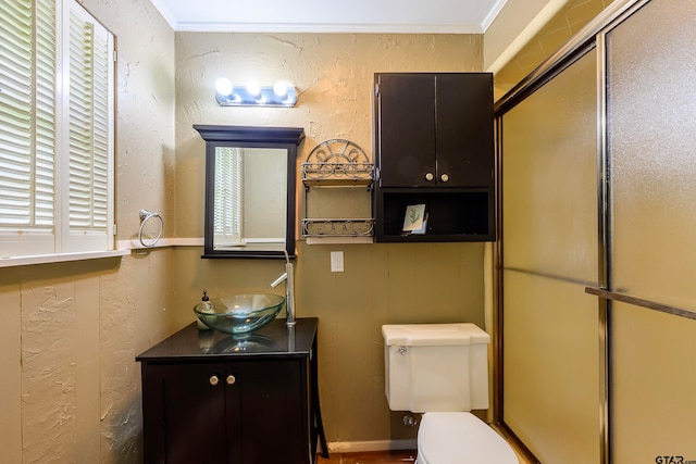 bathroom featuring a shower with door, toilet, vanity, and ornamental molding