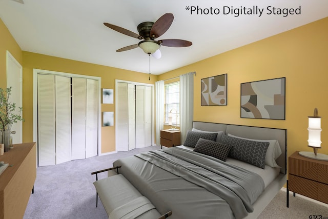 carpeted bedroom featuring two closets and ceiling fan