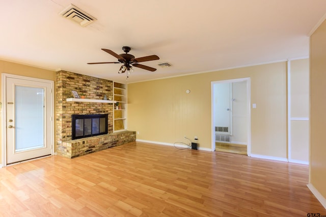 unfurnished living room with built in features, ceiling fan, a brick fireplace, and ornamental molding