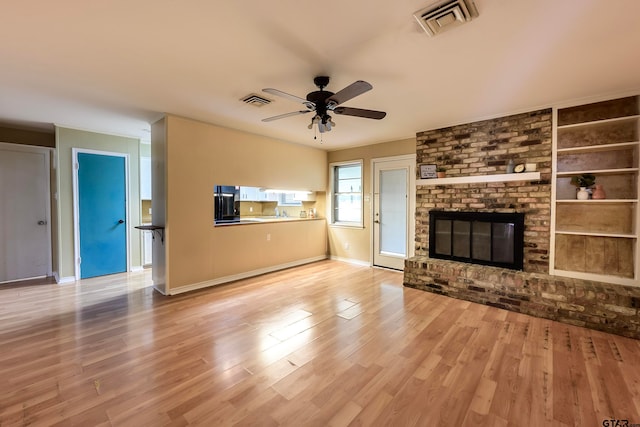 unfurnished living room with ceiling fan, light wood-type flooring, and a brick fireplace