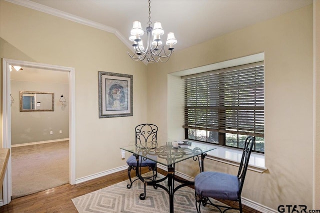 dining area with wood-type flooring, ornamental molding, lofted ceiling, and a notable chandelier