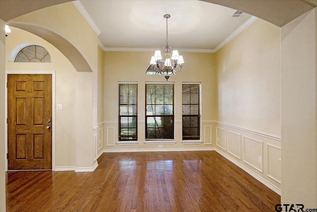 foyer featuring hardwood / wood-style flooring, an inviting chandelier, and ornamental molding