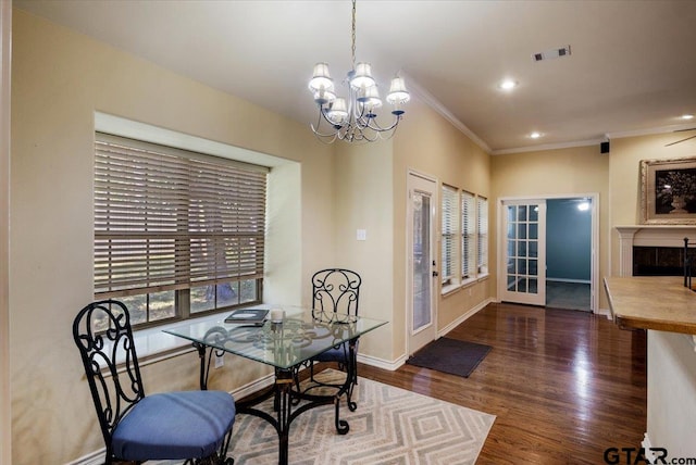 dining space featuring dark wood-type flooring, a notable chandelier, and ornamental molding