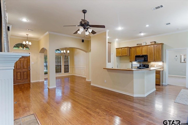 kitchen with ceiling fan with notable chandelier, kitchen peninsula, black appliances, ornamental molding, and light hardwood / wood-style flooring