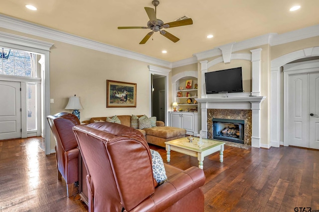 living room featuring a premium fireplace, dark hardwood / wood-style flooring, ceiling fan, and crown molding