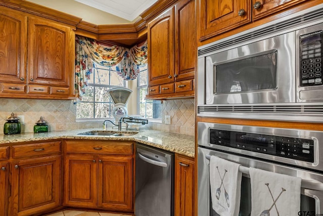 kitchen featuring ornamental molding, stainless steel appliances, light stone countertops, sink, and decorative backsplash