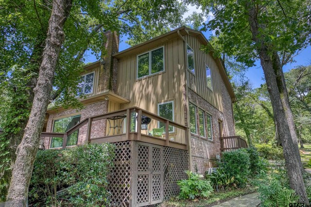 17553 Sleepy Hollow Way, Flint, TX 75762 - back of property featuring brick siding, a chimney, a deck, board and batten siding, and stairway