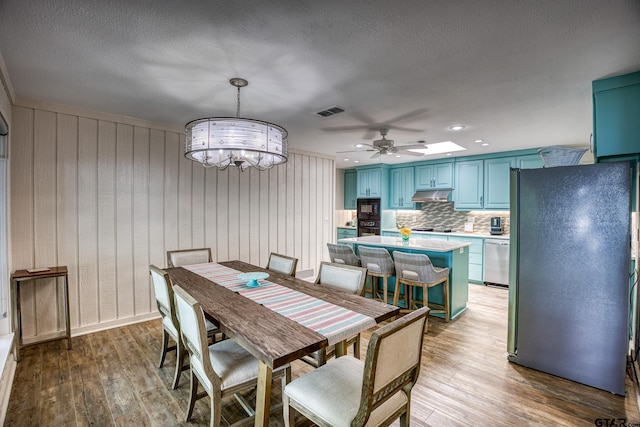 17553 Sleepy Hollow Way, Flint, TX 75762 - dining area with light wood-style floors, ceiling fan, a chandelier, wooden walls, and a textured ceiling